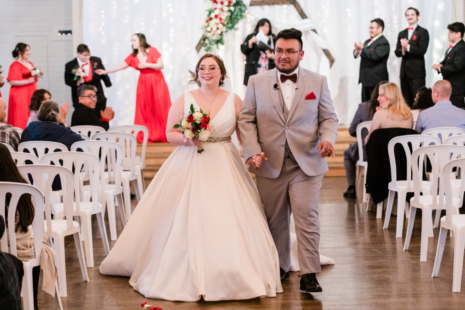 Bride and groom walking back down the aisle as guests applaud at Green Villa Barn in Independence, Oregon