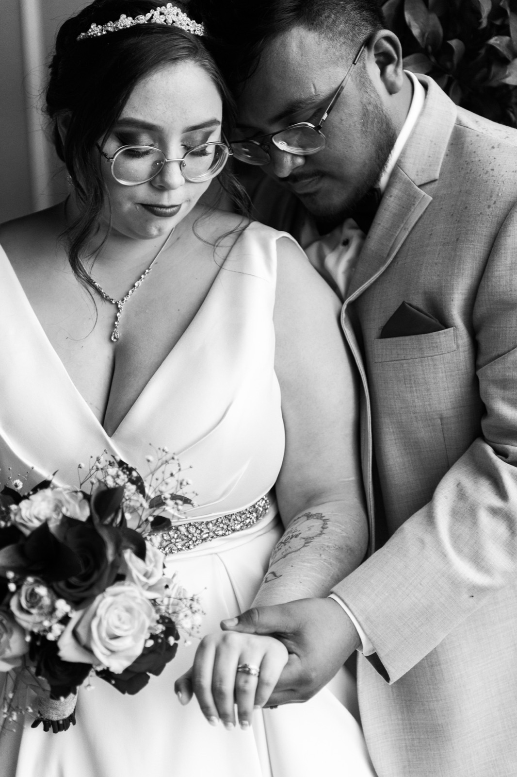 Black and white close-up of a bride and groom looking down at her wedding ring, bouquet in her arm, at Green Villa Barn in Independence, Oregon