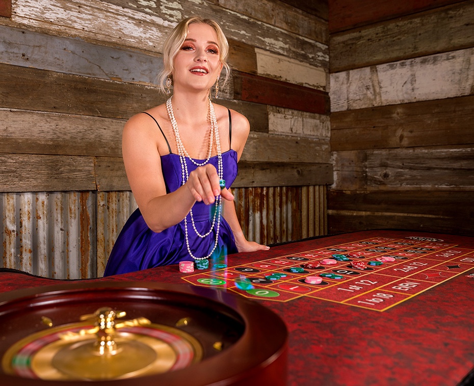 Guest in a purple dress and pearls places her chips on the roulette table at a casino party