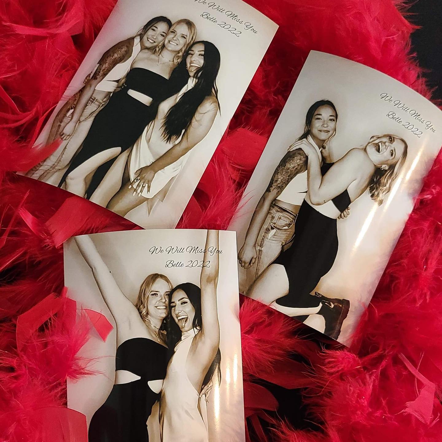 Black and white Glam Booth prints laid on red feather boas