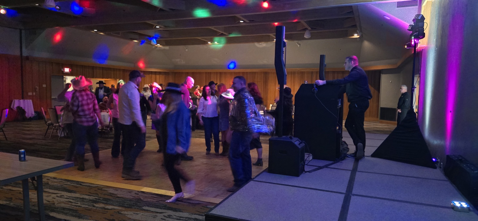 DJ Zach Thomas at his booth as guests dance under colored lights at Salishan