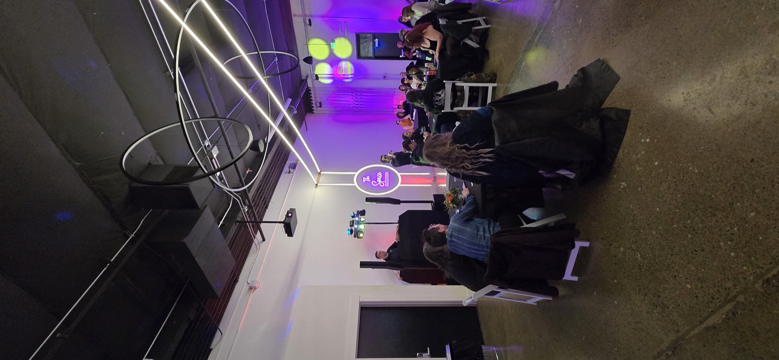 DJ at a black booth with speakers and purple uplighting while guests sit at tables at The Space in Salem, Oregon