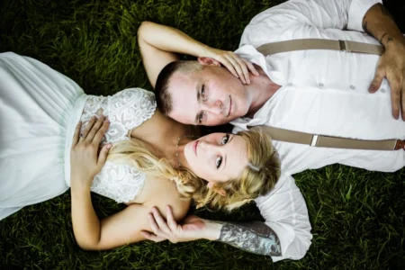 A bride and groom pose in the grass