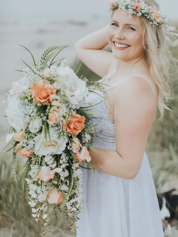 Bride with flowers happily smiling and awaiting for her perfect wedding day