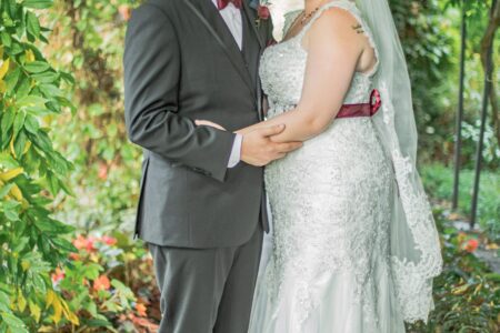A bride and groom pose in a vibrantly green tunneled entrance for wedding portraits.