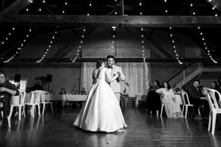 A black and white photo. A bride and groom dance for their first dance.