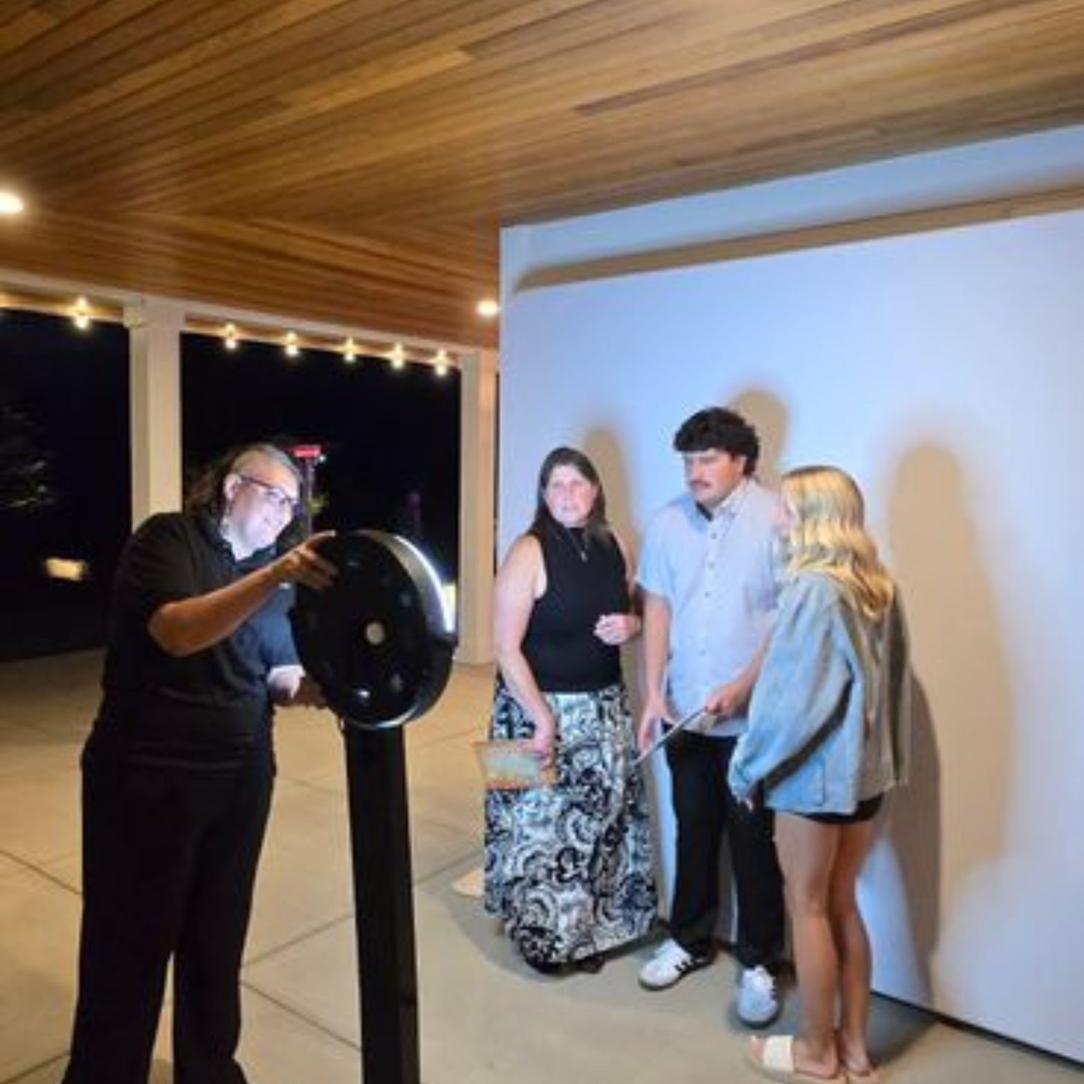 Apogee photo booth tech Kelli takes a photo at an event with some guests in front of a white backdrop.