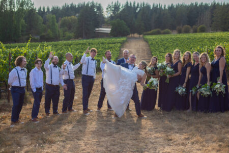 Fun bridal party portrait groom lifting bride at Oregon vineyard wedding groomsmen bridesmaids