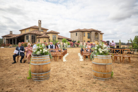 Outdoor ceremony with guests seated at vineyard estate wine barrels DJ sound technician Oregon wedding