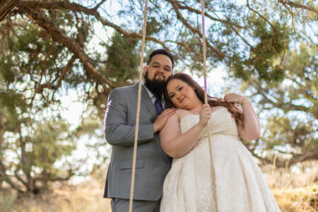 Bride and groom posing on rustic rope swing at Oregon wedding venue with golden sunlight