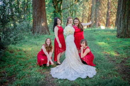 Bride and four bridesmaids in red lace dresses playful portrait in Oregon forest wedding party